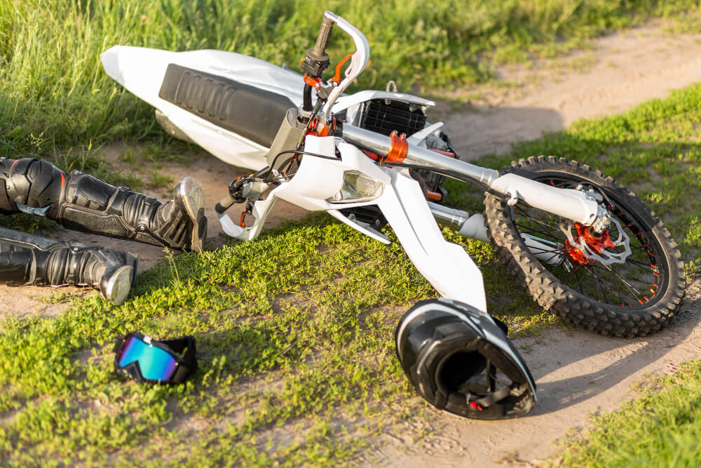 Ein umgestürztes Dirtbike liegt nach einem Motorradunfall in Langen auf einem grasigen Weg, Fahrer und Ausrüstung sind daneben verstreut